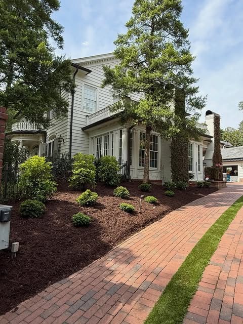 White colonial home with fresh mulch beds and trimmed shrubs